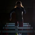 Silhouette of female athlete training with hurdles