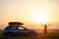 Silhouette of female driver standing near her car on grassy field enjoying view of bright sunset. Young woman relaxing Royalty Free Stock Photo