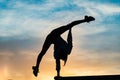 Silhouette of female flexible acrobat doing handstand on the dramatic sunset. Concept of individuality, creativity and