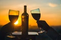 Silhouette of two hands toasting wine on sunset background.