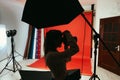 Silhouette of a female photographer in the studio with a camera in her hands on a red background in a photo studio on a background Royalty Free Stock Photo