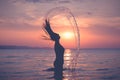 Silhouette of female splashing water with her hair at sunset over sea Royalty Free Stock Photo