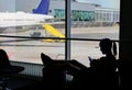 SILHOUETTE Female tourist waiting for her flight and playing games on smartphone