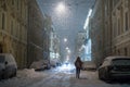 Silhouette of female walking along parked cars on empty evening city street during a snowfall Royalty Free Stock Photo