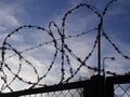 Silhouette of a fence with barbed wire against a blue sky. Prison security. Royalty Free Stock Photo