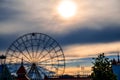 Silhouette of ferris wheel with alone cabin on the blue and orange cloudy sky backgorund against the sunset. Mood