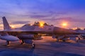 Silhouette fighter jet military aircrafts parked on runway in twilight sunset time with light airport