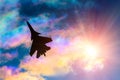 Silhouette of a fighter plane on a background of iridescent sky clouds and sun Royalty Free Stock Photo