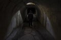 The silhouette of the figure of a man going into unknown darkness in a gloomy dark old underground passage Royalty Free Stock Photo