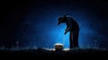 Silhouette of a figure tending to a grave in a moonlit cemetery Royalty Free Stock Photo