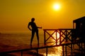 silhouette of a figure of a woman in a bathing suit on a wooden pier against the backdrop of the dawn sun on the sea Royalty Free Stock Photo