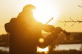 Silhouette figure of a young violinist in a jacket at sunset, a man playing the violin in nature, music and art concept