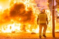 Silhouette of fireman trying to control a fire in a street during a night