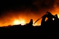 Silhouette of Firemen fighting a raging fire