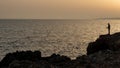 Silhouette of a fisher fisheman fishing in the ocean at sunset Royalty Free Stock Photo