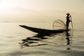 The silhouette of a fisherman on a boat in the morning at Inle Lake is a fresh water lake In the mountainous area