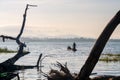 Silhouette fisherman on boat over bang phra reservoir near dead tree