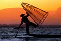 Silhouette of a fisherman in a boat with traditional Intha conical net in Myanmar