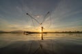 Silhouette Fisherman casting or throwing a net for catching freshwater fish in nature lake or river with reflection in morning