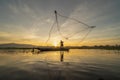 Silhouette Fisherman casting or throwing a net for catching freshwater fish in nature lake or river with reflection in morning Royalty Free Stock Photo