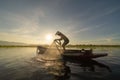 Silhouette Fisherman casting or throwing a net for catching freshwater fish in nature lake or river with reflection in morning Royalty Free Stock Photo