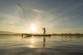 Silhouette Fisherman casting or throwing a net for catching freshwater fish in nature lake or river with reflection in morning Royalty Free Stock Photo