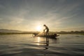 Silhouette Fisherman casting or throwing a net for catching freshwater fish in nature lake or river with reflection in morning Royalty Free Stock Photo