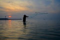 Silhouette fisherman catch fish in the sea and sunset background Royalty Free Stock Photo