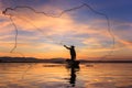 Silhouette fisherman on fishing boat setting net with sunrise