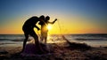 Silhouette fisherman fishing net on the sunset beach