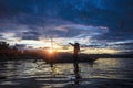 Silhouette Fisherman Fishing by using Net on the boat with sunlight in Thailand , Nature and Culture concept Royalty Free Stock Photo