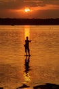 Silhouette fisherman of Lake in action when fishing.