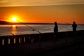 Silhouette of fisherman over sunset in city port