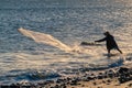 silhouette of fisherman pulling his trammel net on the beach shore, during sunset Royalty Free Stock Photo