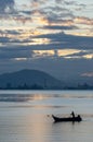 Silhouette Fisherman row boat in the sea with background Bukit Mertajam hill. Royalty Free Stock Photo