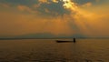 Silhouette fisherman with rowboat, dramatic sunset on the lake, beautiful peaceful scene, bright sun light. Royalty Free Stock Photo