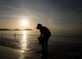 Silhouette of fisherman searching for shells on the beach during sunrise in Phuket