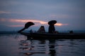 Silhouette of fisherman at sunrise, Standing aboard a rowing boat and casting a net to catch fish