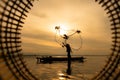 Silhouette of fisherman at sunrise, Standing aboard a rowing boat and casting a net to catch fish