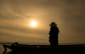 Silhouette of fisherman at sunrise, Standing aboard a rowing boat and casting a net to catch fish