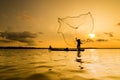 Silhouette of a fisherman throwing his net with sunset. Royalty Free Stock Photo