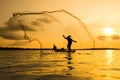 Silhouette of a fisherman throwing his net with sunset. Royalty Free Stock Photo