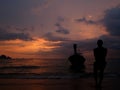 Silhouette of fisherman and traditional Thai longtail boat on sunset background on beach in krabi province Royalty Free Stock Photo