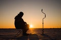 Silhouette of a fisherman on winter ice fishing at sunset. Royalty Free Stock Photo