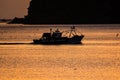 Silhouette of fishermen boat on Mediterranean Sea during sunrise in golden sun rays in MDiq, Morocco