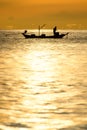 Silhouette of fishermen in the boat on sea with yellow and orange sun in the background Royalty Free Stock Photo