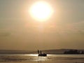 Silhouette of fishermen on a boat with yellow and orange sun in the background Royalty Free Stock Photo