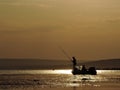 Silhouette of fishermen on a boat with yellow and orange sun in the background Royalty Free Stock Photo