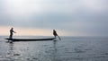 Silhouette of fishers paddling by legs on Inle lake, Myanmar