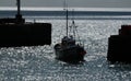 Silhouette of fishing boat entering harbor.